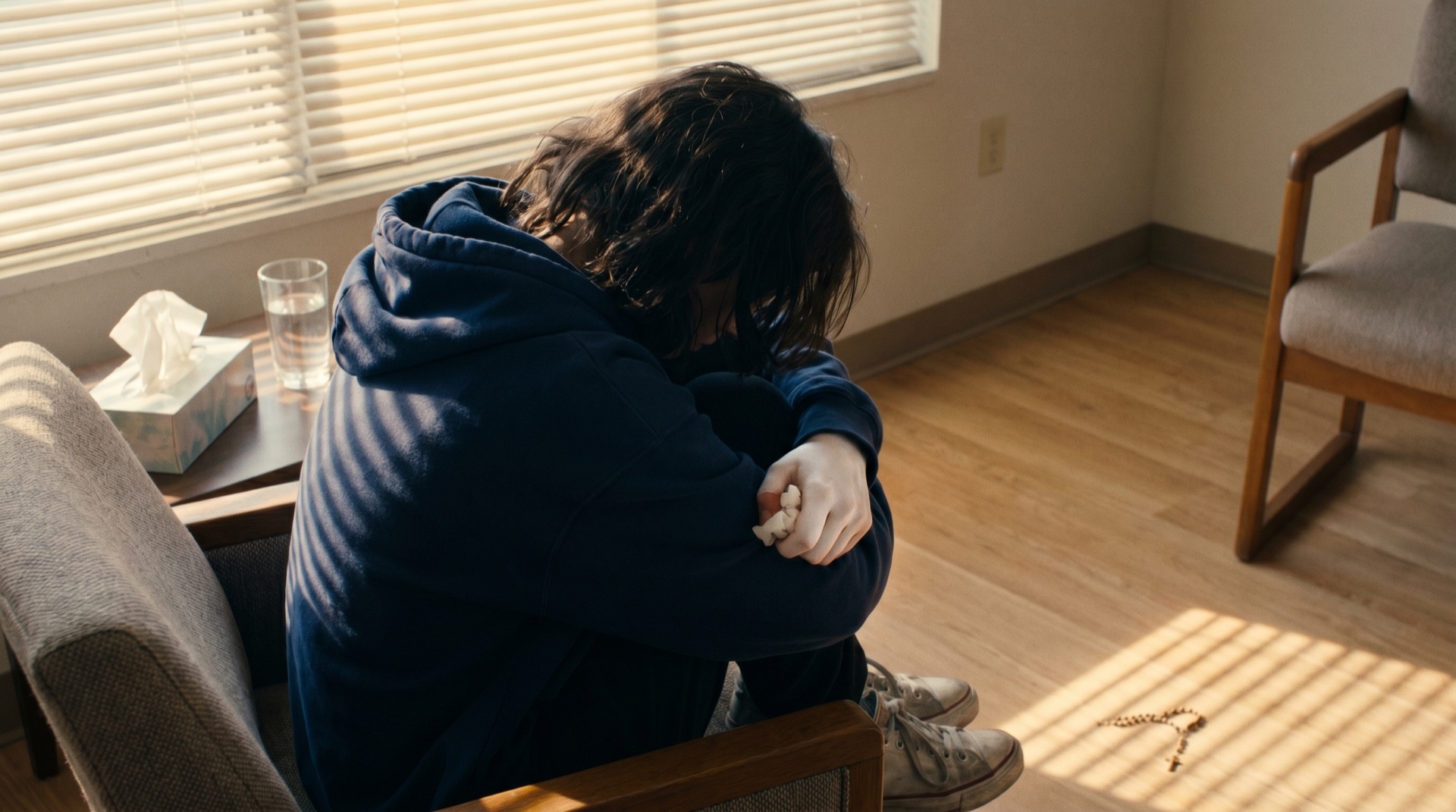 A frightened teenage girl curled in a sparse room